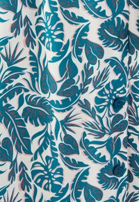 Tissu à motif floral présentant des feuilles teal foncé et roses sur un fond blanc, avec un détail de bouton proéminent. Texture lisse.