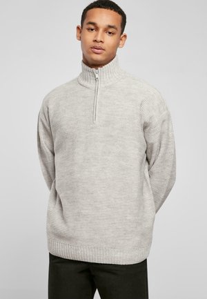 Lys grå pullover-sweater med høj krave og halv lynlås, med et struktureret strikkemønster samt ribbede manchetter og kant.