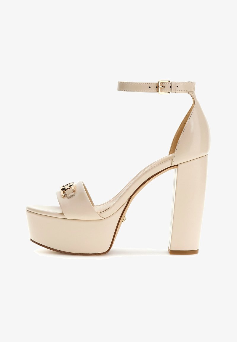 Tacco platform in pelle lucida beige con cinturino alla caviglia e un accento dorato sulla fascia anteriore. Tacco a blocco robusto. Texture liscia.