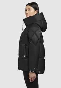 Black puffer jacket with a high collar and hood. Textured, quilted design with side pockets. Smooth, shiny material and zipper details.