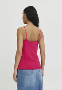 Fuksia tanktop, jossa on ohuet säädettävät hihnat, valmistettu sileästä kankaasta; yhdistettynä denimhameeseen, jossa on takataskut ja suora leikkaus.