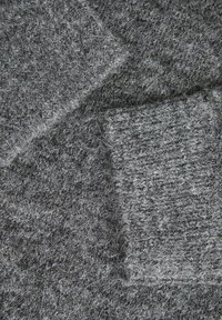 Tessuto grigio a maglia con una superficie texture, caratterizzato da diverse sfumature di grigio e un aspetto peloso. Strati multipli sovrapposti.