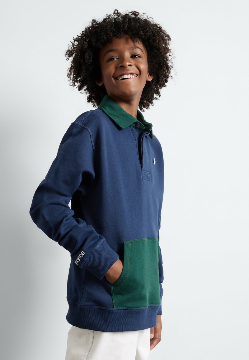 Marineblauwe pullover met een groene kraag en een zak aan de voorkant. Heeft een ontspannen pasvorm, lange mouwen en een klein logo op de borst.