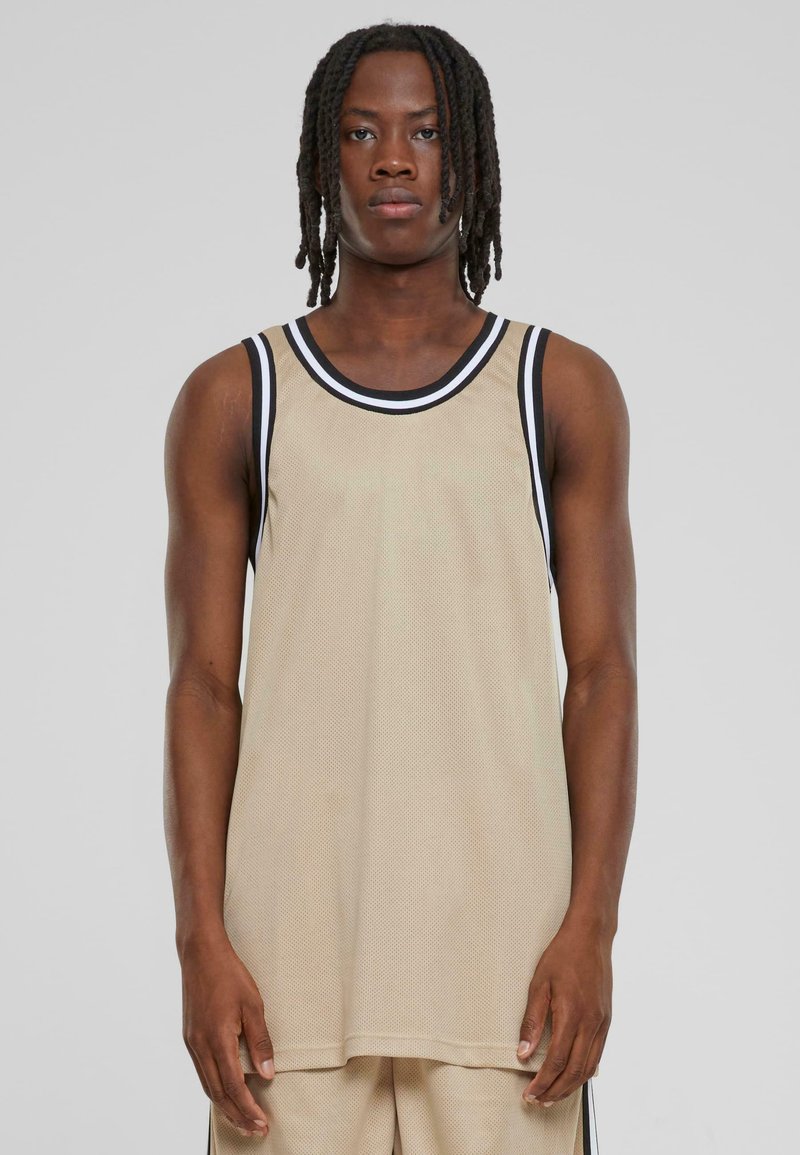 Beige netting tank topp med svart og hvit kant, med løs passform og uten ermer. Merkbar tekstur og pustende materiale.