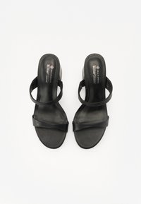 Sandales en cuir vegan noir avec deux fines lanières et une semelle intérieure en forme. Le talon est en forme de bloc pour un soutien et une stabilité accrus.