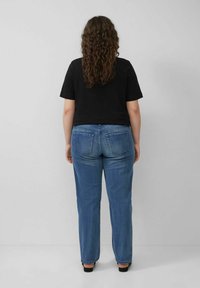 Schwarzes, kurzes T-Shirt mit kurzen Ärmeln, kombiniert mit hochtaillierten, hellblauen Jeans, die zwei Gesäßtaschen und einen geraden Bein design aufweisen.