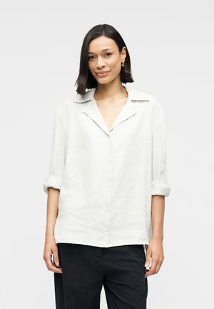 Ανοιχτό γκρι λινό πουκάμισο με άνετη εφαρμογή, ρεβέρ μανικιών και μυτερό γιακά, με κουμπιά στο μπροστινό μέρος και απαλή υφή.