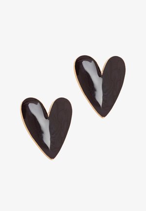 Paire de boucles d'oreilles clous en émail noir en forme de cœur avec des bords dorés sur un fond blanc.