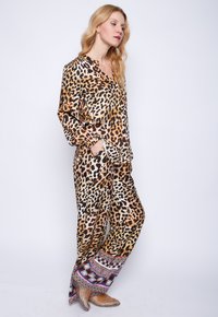 Leopardenmuster-Pyjama-Set aus Seide, mit langen Ärmeln, Knopfleiste und gemusterten Manschetten mit geometrischen Designs. Weiche Schimmer-Oberfläche.