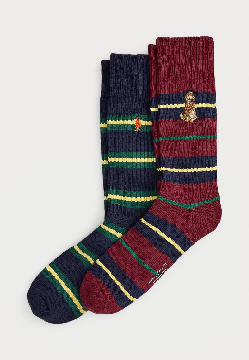 Divas joslu pāri svītrainām zeķēm: vienas tumši zilas ar zaļām un dzeltenām svītrām un oranžu polo spēlētāja logo, otrās bordo ar tumši zilām, zaļām un dzeltenām svītrām un suņa logo.