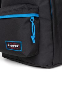 Zaino Eastpak nero con una tasca frontale dotata di cerniera blu e dettagli in blu, tessuto testurizzato e un'etichetta logo ben visibile.