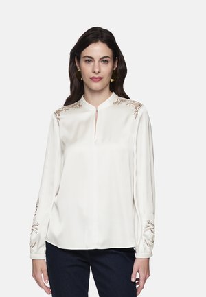 White silk blouse with a mandarin collar, long sleeves, and brown floral embroidery on shoulders and sleeves. Smooth texture, relaxed fit.