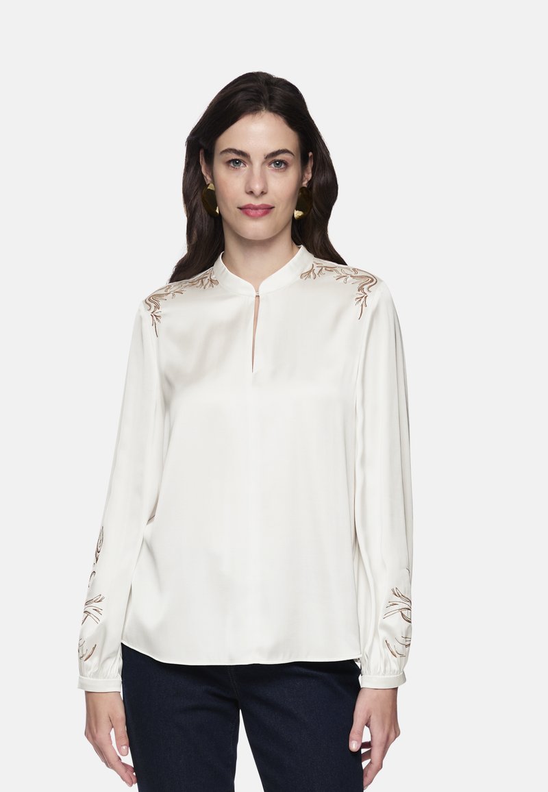 White silk blouse with a mandarin collar, long sleeves, and brown floral embroidery on shoulders and sleeves. Smooth texture, relaxed fit.