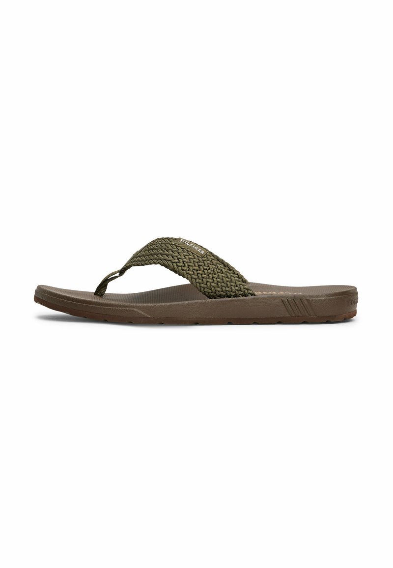 Brun flip-flop sandal med en vævet grøn rem, flad design, tekstureret sål og en fleksibel gummisål. Har branding på remmen.