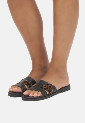 Chanclas negras con detalles de estampado de leopardo, con suelas planas y un diseño de tiras cruzadas. Textura suave con estilo de punta abierta.