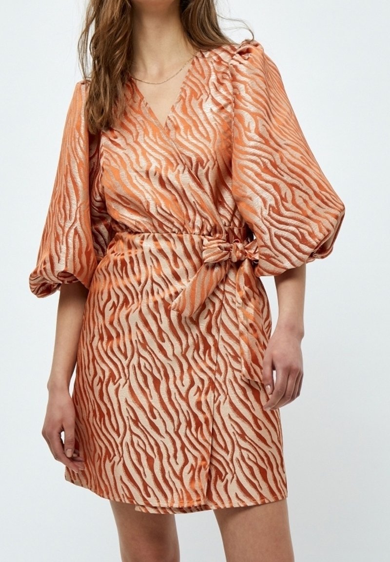Kortärmad klänning i orange och beige med tigerstripemönster, med en omslagdesign och en knytning i midjan. Slät textur.