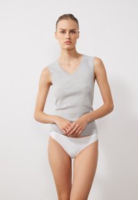 Top gri fără mâneci, cu decolteu în V și textură riglată, purtat cu lenjerie albă. Design simplu, fără modele sau accente.
