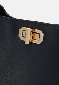 Black leather handbag featuring a textured surface and a metallic gold-toned fastening with geometric accents.