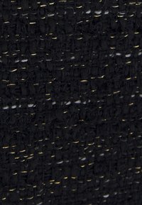 Svart vävd tyg med en strukturerad yta, med subtila guldtrådsdetaljer. Mönstret består av en tät rutnätsliknande väv.