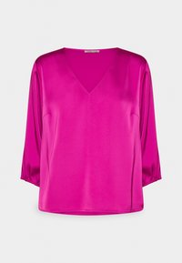 Blouse en satin fuchsia avec un décolleté en V et des manches trois-quarts. Le tissu a une texture lisse et une coupe légèrement ample.