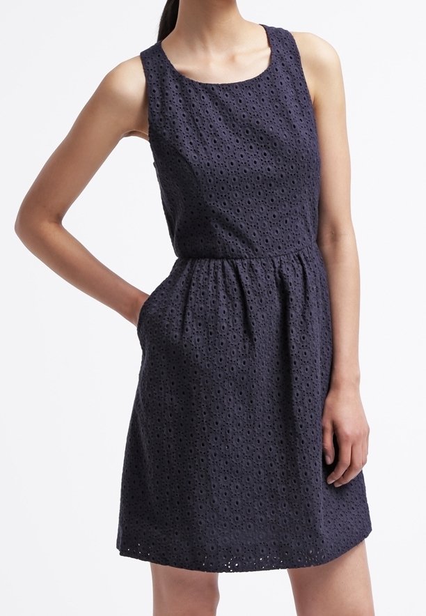 Laakulinen, sininen, ilman hihoja oleva mekko, jossa on silmukka kangasta, pyöreä pääntie, kireä vyötärö ja sivutaskut; mekko laskeutuu polven ylle ja siinä on liehuva siluetti.