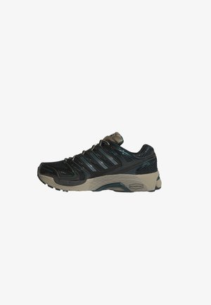 Scarpa da ginnastica atletica nera e verde scuro con tomaia in mesh, suola beige texturizzata e più strisce laterali, vista dal lato esterno.