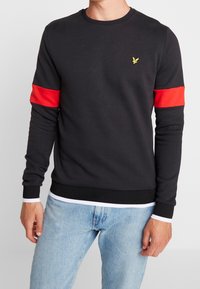 Felpa nera con strisce orizzontali rosse sulle maniche, collo rotondo, polsini a coste e un piccolo logo giallo sul petto.