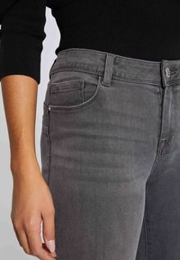 Jeans in denim grigio con un design aderente, caratterizzati da cinque tasche, una leggera sfumatura e una chiusura con zip e bottone.