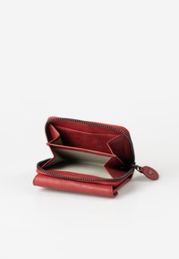 Red leather wallet with a zip closure. Interior features a beige lining and two compartments for cards or cash. Compact design.