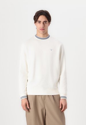 Sweater in cream cotton with ribbed navy-and-white striped collar and cuffs, featuring a small logo on the chest. Casual fit.