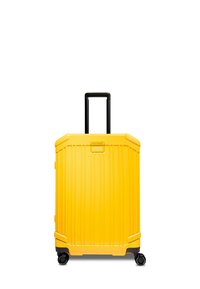 Valigia a cabina gialla con guscio rigido, texture a righe verticali, manico nero retrattile e quattro ruote nere per una facile mobilità.