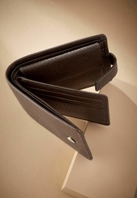 Portefeuille en cuir marron avec finition texturée, design pliable, fermeture à bouton et plusieurs emplacements pour cartes. Exposé sous un angle sur un fond neutre.