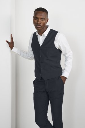 Navyblauer Anzugwesten über einem weißen Hemd, mit einer sechsknöpfigen Front, slim-fit Design und glattem Stoff, kombiniert mit maßgeschneiderten Hosen.