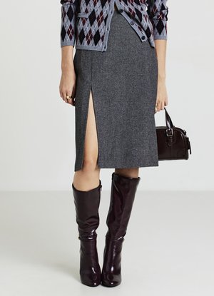Grauer Wollbleistiftrock mit seitlichem Schlitz, kombiniert mit glänzenden burgunderfarbenen Stiefeln bis zum Knie und einer kleinen dunklen Handtasche. Texturiertes Cardigan darüber.