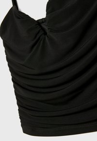 Top nero in tessuto arricciato con scollatura profonda e spalline sottili. Texture liscia con dettagli arricciati lungo la scollatura e i lati.