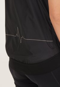 Schwarze Sportweste mit einem Herzschlaggrafik in Weiß, mit strukturiertem Finish und elastischem Saum für eine taillierte Passform.