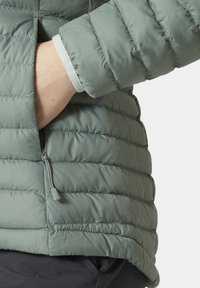 Zelená péřová bunda s horizontálním prošíváním, obsahující boční kapsu na zip a elastické manžety. Měkká, lehká textilie.