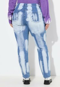 Světle obarvené džíny z denimu s tie-dye vzorem bílých pruhů. Vysoký pas, zadní kapsy, zúžené nohavice a mírné obnošení.