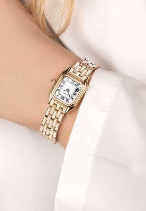 Goldfarbene Metalluhr mit rechteckigem Gehäuse, weißem Ziffernblatt, schwarzen römischen Ziffern und einem verlinkten Armband, das um ein Handgelenk gelegt ist.