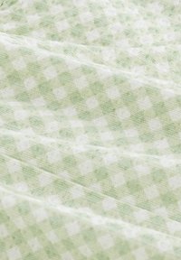 Vihreä ja valkoinen ruudullinen kangas, jossa on pehmeä rakenne ja pieniä neliöitä sisältävä ruudukkomalli, taiteltuna syvyyden ja kerrosten esittelemiseksi.