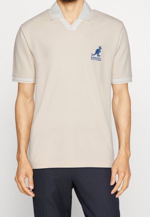 Beige Poloshirt mit hellgrauem Kragen und Ärmeln. Mit blauem Kangol-Logo auf der linken Brust. Aus glattem Stoff gefertigt.