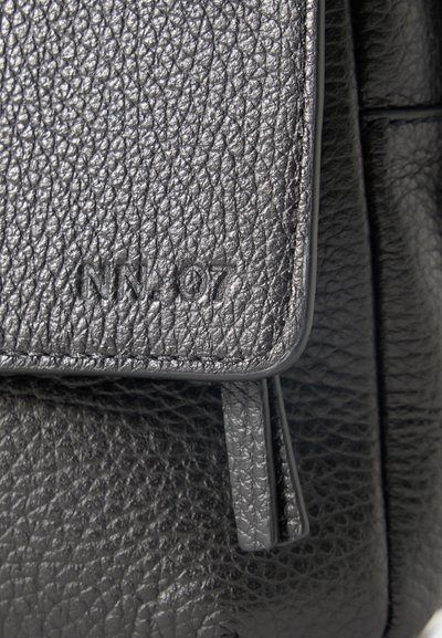 Κοντινή λήψη μαύρης υφασμάτινης δερμάτινης πτέρυγας τσάντας με ανάγλυφο "NN-07" και ραμμένα άκρα.