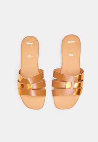 Sandali in pelle tan con più cinturini sovrapposti, accentuati da un quadrato e una soletta piatta. Logo impresso sulla suola interna.