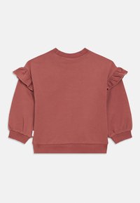 Hette tröja i dammig rosa med volangdetaljer på axlarna, ribbade ärmslut och nederkant. Mjuk textur, rund hals och avslappnad passform.