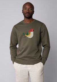 Olivengroen sweatshirt met een geometrisch vogelontwerp in rood, geel, groen en crème. Heeft een ronde hals en geribbelde manchetten. Effen achtergrond.