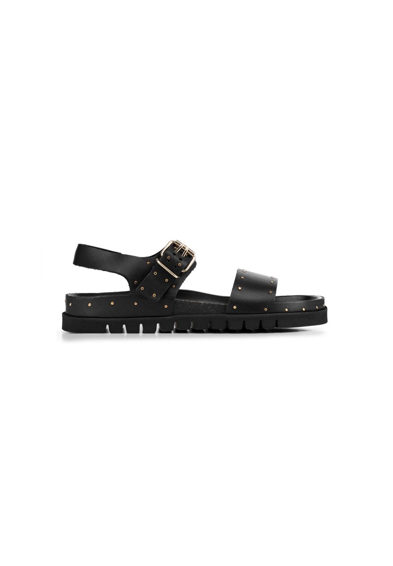 Sandali in pelle nera con suola piatta, borchie dorate e chiusura con fibbia laterale, con un retro aperto e cinturini larghi.