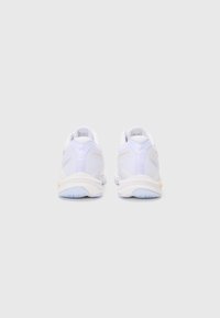 Baskets blanches de sport avec une tige en mesh texturé, des accents orange clair et une semelle en caoutchouc avec un motif de traction bleu.