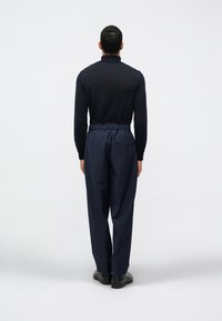 Calças da marinha com cintura elástica e uma camisa preta de manga longa ajustada. Textura suave, design minimalista e detalhes de costura subtis.