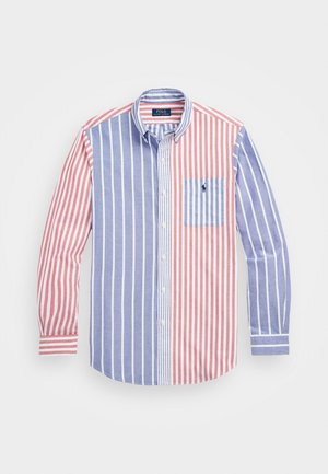 Camisa de botones con rayas verticales en rojo y azul, con un pequeño bolsillo en el pecho y un logo de polo en el lado izquierdo. Material de algodón.