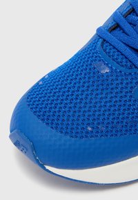 Chaussure de sport bleue avec une tige en mesh texturé, des accents en caoutchouc lisses, un bout arrondi et une semelle blanche contrastante.